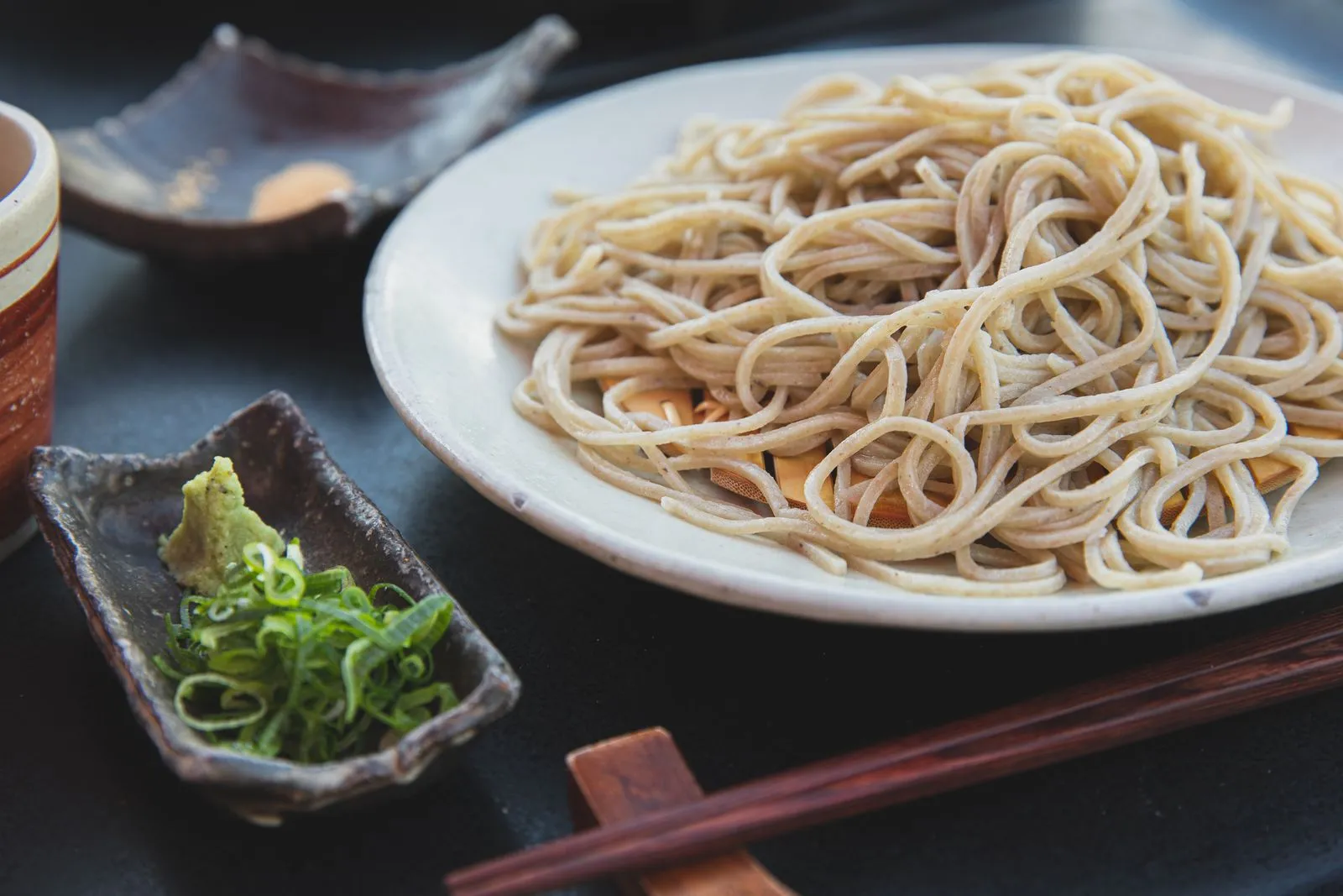 Fresh pasta on ceramic plate and wakame salad near chopsticks on table in restaurant